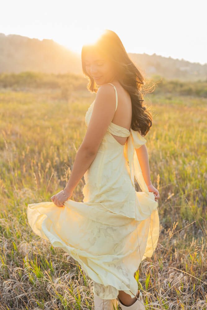 senior photoshoot during sunset in a field with a girl in pretty dress